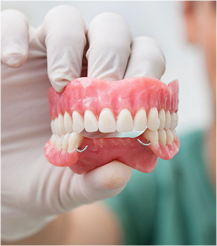 Hand with white glove displaying denture model.